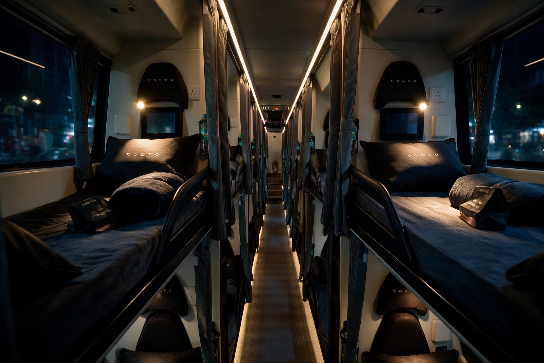 Interior of zingbus Maxx premium sleeper bus with reclined berths, personal screens and reading lights at night