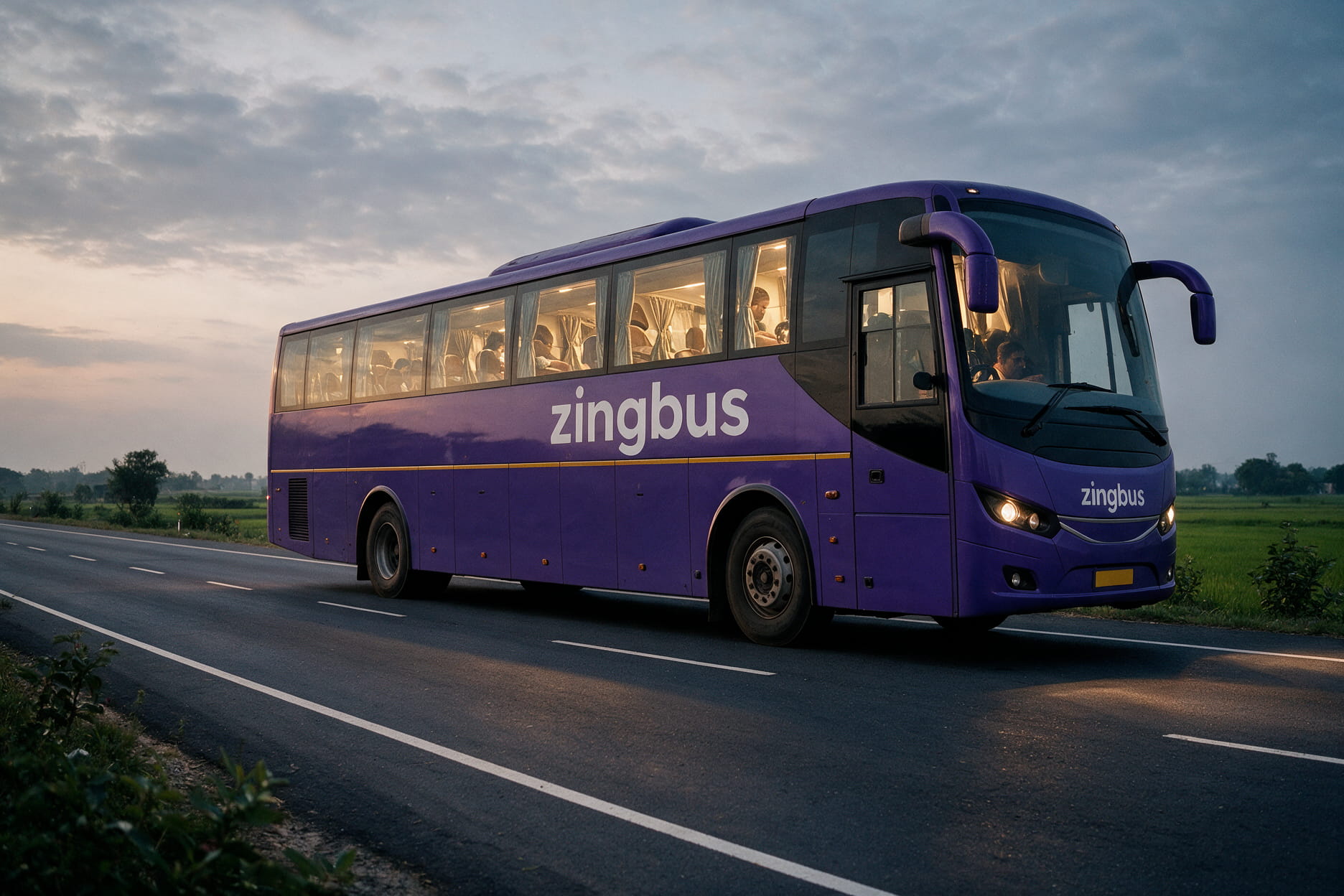 An air conditioned sleeper coach on a national highway in eastern Uttar Pradesh at dusk with fields alongside