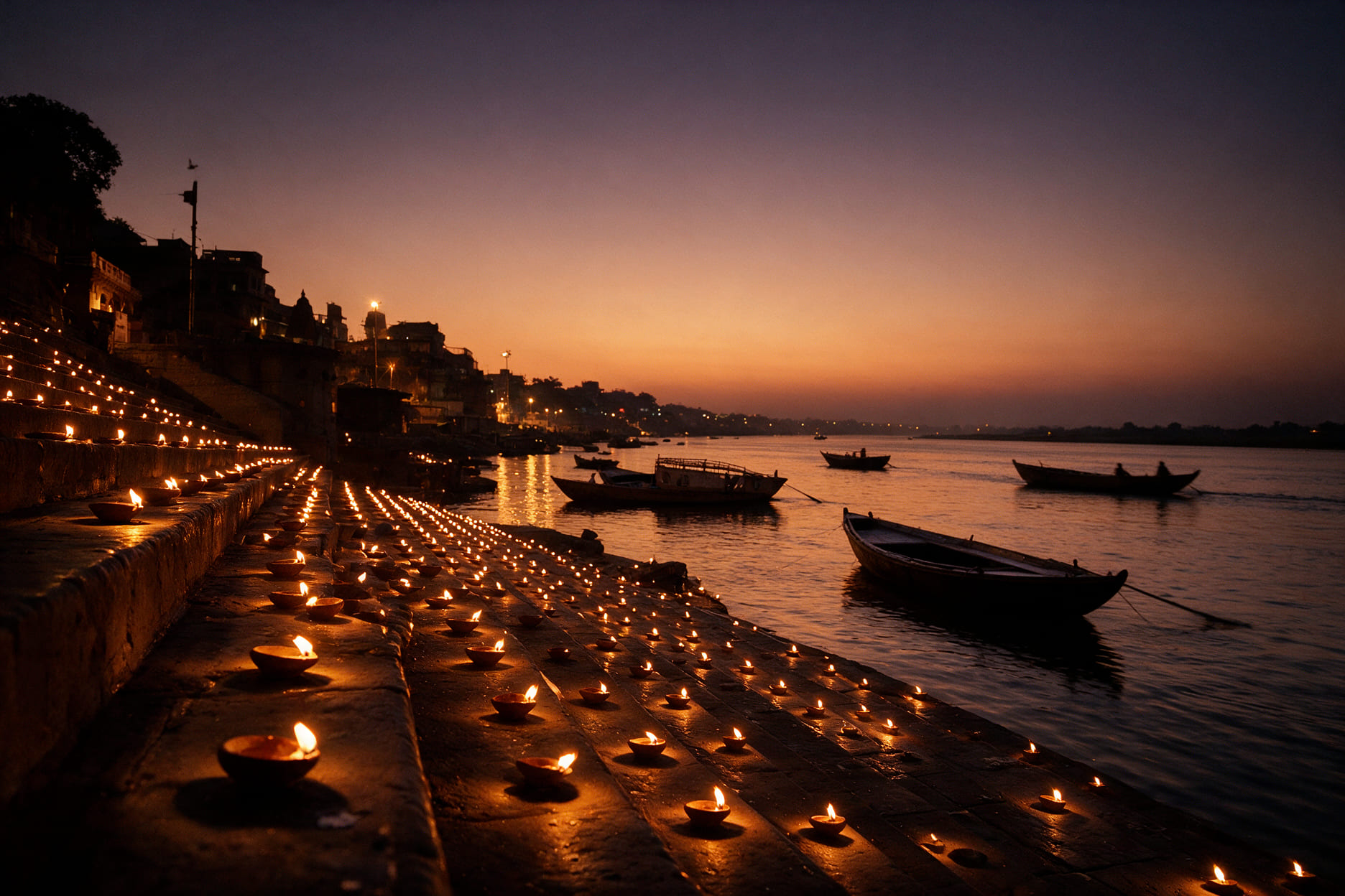 Rows of earthen lamps burning on the stone steps of a Varanasi ghat with boats on the Ganga at dusk